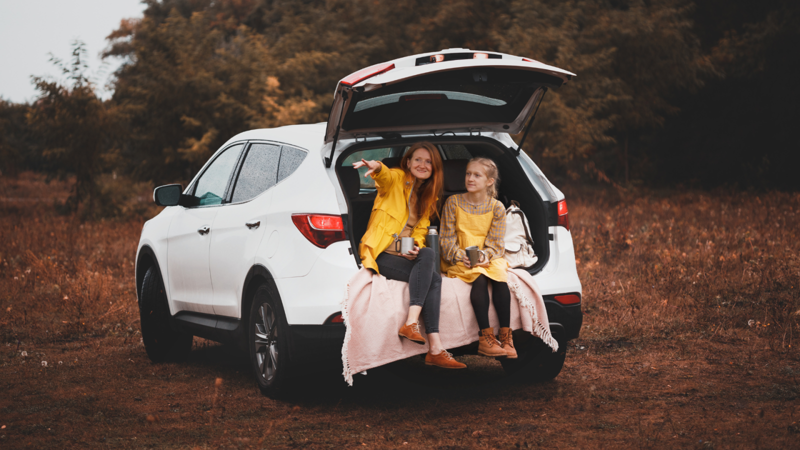 A mum and her daughter sitting in the boot of a car